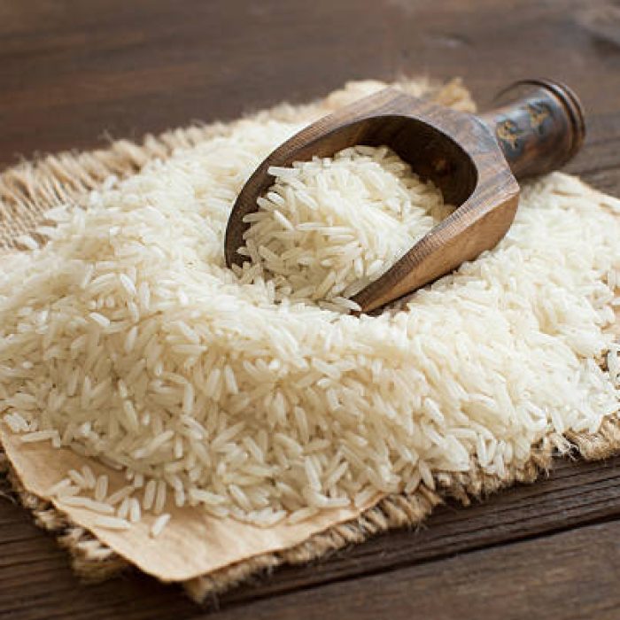 Pile of raw Basmati rice with a spoon close up